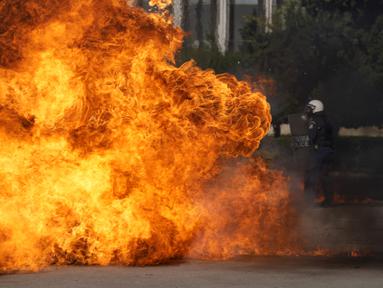 Sebuah bom molotov meledak di dekat polisi anti huru hara di luar Parlemen Yunani selama bentrokan di Athena, Yunani (9/11/2022). Ribuan pengunjuk rasa berbaris melalui jalan-jalan Athena dan kota Thessaloniki di Yunani utara sebagai pekerja publik dan beberapa sektor swasta meninggalkan pekerjaan untuk pemogokan umum 24 jam terhadap kenaikan harga.  (AP Photo/Petros Giannakouris)