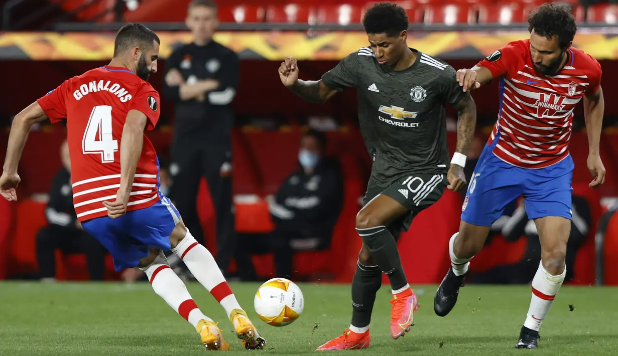 Penyerang Manchester United, Marcus Rashford berusaha melewati pemain Granada, Maxime Gonalons pada pertandingan leg pertama perempat final Liga Europa di stadion Los Carmenes di Granada, Spanyol, Jumat (9/4/2021). MU menang atas Granada 2-0. (AP Photo/Fermin Rodriguez)