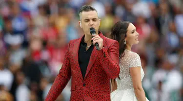 Penyanyi asal Inggris, Robbie Williams, berduet dengan penyanyi soprano Rusia Aida Garifullina pada upacara pembukaan Piala Dunia 2018 di Stadion Luzhniki, Moskow, Kamis (14/6). Keduanya berkolaborasi di lagu Angel milik Williams. (AP/Pavel Golovkin)