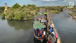 Perahu wisata melintasi kerumunan wisatawan yang berjalan di atas Jembatan Cinta di Wisata Mangrove, Tarumajaya, Bekasi, Minggu (30/12). Wisata tersebut menyajikan hutan mangrove dan makanan khas. (merdeka.com/Arie Basuki)