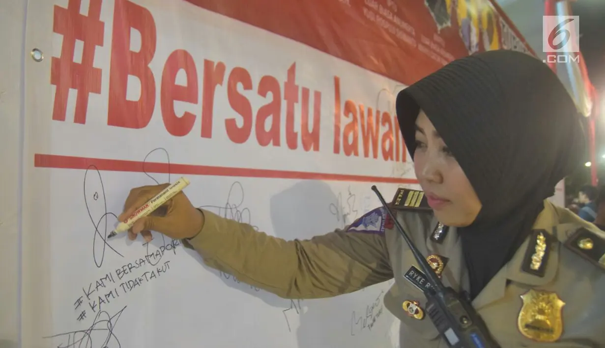 Seorang polwan menandatangani spanduk saat tablig akbar di Simpang Lima, Kota Semarang, Minggu (13/5). Spanduk tersebut bentuk dukacita untuk korban teror di Mako Brimob, Jakarta beberapa waktu lalu dan teror bom gereja di Surabaya. (Liputan6.com/Gholib)