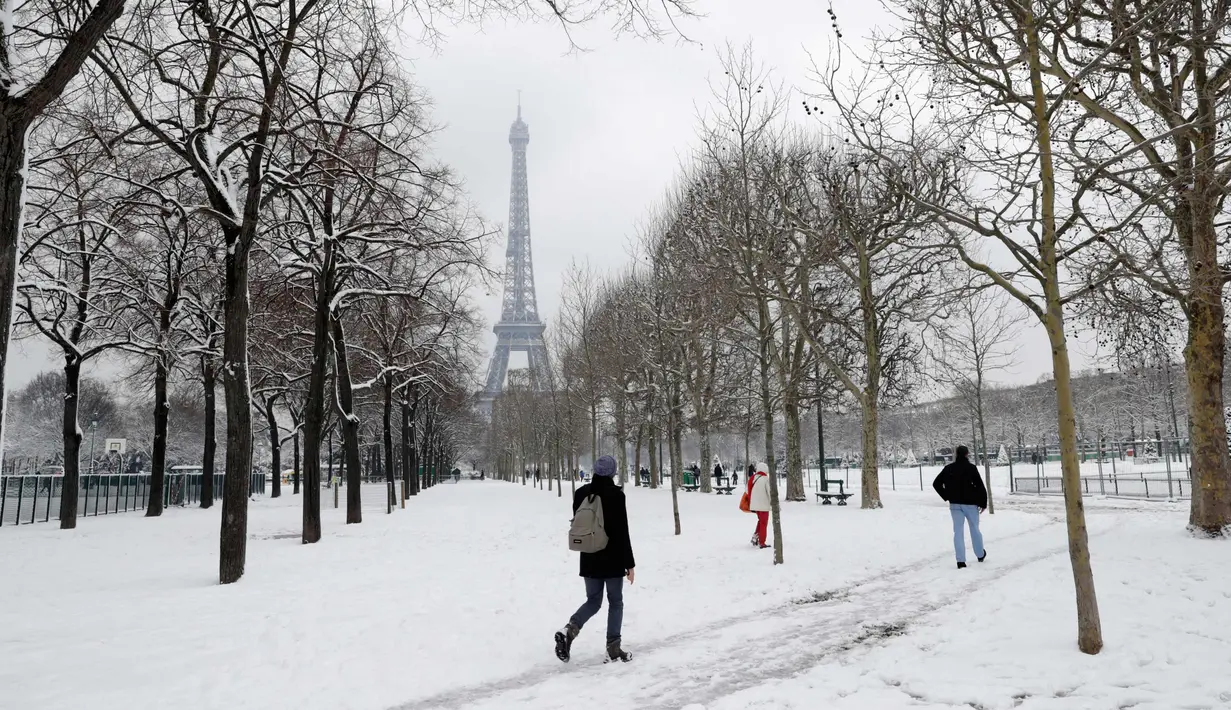 Aktivitas warga saat hujan salju di bawah Menara Eiffel di Paris, Prancis (7/2). Hujan salju yang sangat lebat membuat transportasi umum di paruh utara Prancis dan di Paris tidak dapat beroperasi. (AFP Photo / Thomas Samson)
