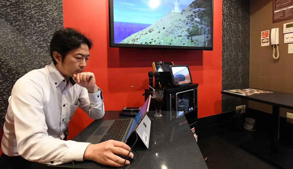Foto 30 Agustus 2018, pengusaha Hideyuki Aoki bekerja di dalam ruangan karaoke sewaan di Tokyo, Jepang. Pengguna bisa menampilkan gambar langsung dari komputer atau laptop mereka ke layar yang biasa menampilkan lirik lagu. (Toshifumi KITAMURA/AFP)