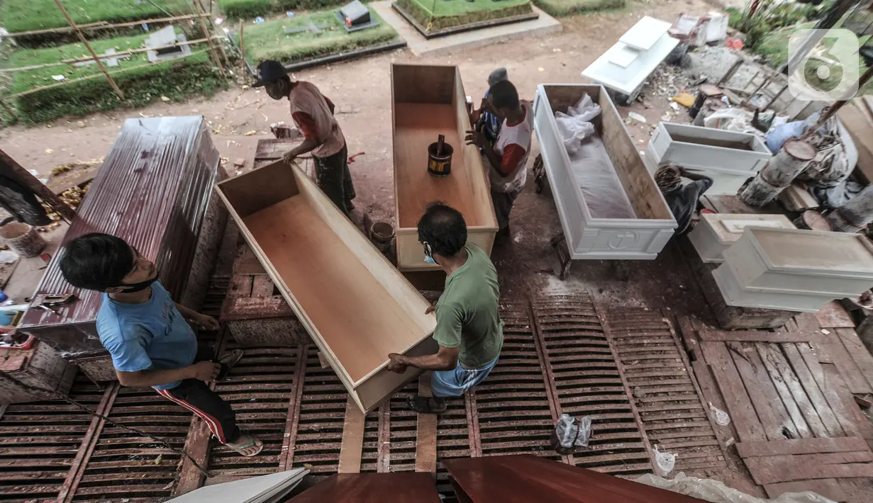 Pekerja menyelesaikan pembuatan peti jenazah di TPU Pondok Kelapa, Jakarta, Selasa (13/7/2021). Melonjaknya angka kematian Covid-19 di Ibu Kota beberapa hari terakhir, menyebabkan jumlah permintaan peti jenazah kembali meningkat hingga membuat pasokan bahan baku menipis (merdeka.com/Iqbal S Nugroho)