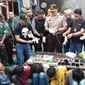 Petugas menunjukkan barang bukti dalam penggerebekan Kampung Boncos, Kota Bambu Selatan, Palmerah Jakarta Barat, Rabu (7/2). (Liputan6.com/ Ady Anugrahadi)