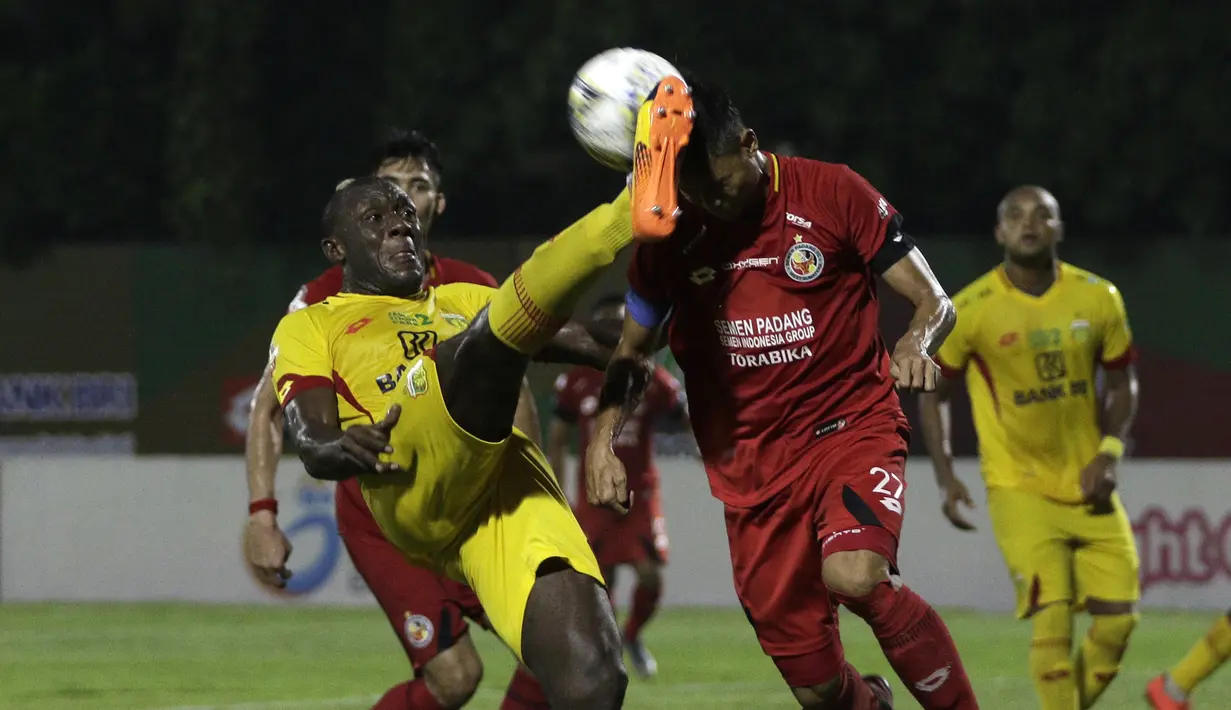 Striker Bhayangkara FC, Herman Dzumafo, berebut bola dengan bek Semen Padang, Dedy Gusmawan, pada laga Shopee Liga 1 di Stadion PTIK, Jakarta, Sabtu (2/11). Bhayangkara bermain imbang 2-2 atas Semen Padang. (Bola.com/Yoppy Renato)