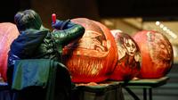Seorang seniman mengukir labu dalam acara Malam 1.000 Jack-O'-Lantern di Chicago Botanic Garden, Glencoe, Illinois, Amerika Serikat, 24 Oktober 2020. Lebih dari 1.000 labu ukiran tangan dipamerkan di acara tersebut menjelang perayaan Halloween. (Xinhua/Joel Lerner)