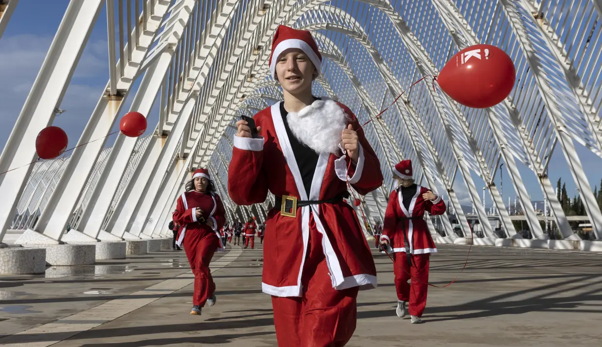Orang-orang dengan kostum Sinterklas berlari di jalan setapak dari kubah baja, yang disebut Agora, selama Athens Santa Run di Athena, Yunani, Minggu (12/12/2021). Ratusan orang mengikuti lomba lari untuk acara amal di area sekitar kompleks Stadion Olimpiade Athena. (AP Photo/Yorgos Karahalis)