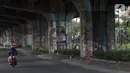 Pengendara motor melintasi sisi tiang penyangga Jalan Tol Pelabuhan Lingkar Dalam Jakarta di Jalan Ancol Timur, Jakarta, Selasa (16/6/2020). Seni mural yang dulu menghiasi tiang-tiang jalan tol di kawasan tersebut kini terlihat kusam dan berdebu. (Liputan6.com/Helmi Fithriansyah)