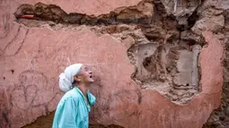 Seorang wanita bereaksi di depan rumahnya yang rusak akibat gempa bumi di kota tua Marrakesh pada 9 September 2023. Gempa kuat yang mengguncang Maroko pada 8 September menewaskan lebih dari 600 orang, menurut data kementerian dalam negeri, dan membuat warga yang ketakutan melarikan diri dari rumah mereka di tengah malam. (FADEL SENNA/AFP)