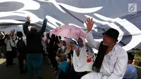 Sejumlah peserta aksi 299 berteduh di bawah bendera putih berlafazkan tauhid saat berkumpul di depan MPR/DPR, Senayan, Jakarta, Jumat (29/9). Aksi  ini diikuti berbagai elemen masyarakat dari Jabodetabek maupun dari luar daerah. (Liputan6.com/JohanTallo)