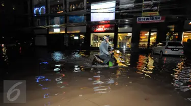 Seorang pengendara motor menerobos banjir yang menggenangi kawasan Kemang, Jakarta, Minggu (25/9). Hujan deras yang mengguyur sebagian besar kawasan di Jakarta, Minggu malam, membuat wilayah Kemang terendam banjir lagi. (Liputan6.com/Helmi Afandi)