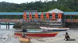 Warga duduk di pinggir pantai dekat tulisan 'Welcome to Bunaken' di Pulau Bunaken, Manado, Sabtu (17/12). Pemprov Sulut gencar melakukan promosi pariwisata dengan tujuan mendatangkan turis sebanyak mungkin hingga ke Tiongkok. (Liputan6.com/Fery Pradolo)