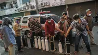 Warga mengantre untuk mengisi ulang tabung oksigen di stasiun pengisian di kota Surabaya, Kamis (15/7/2021). Di Surabaya, masih banyak permintaan isi ulang oksigen, baik tabung kecil 0,5–1 meter kubik hingga ukuran besar 6–7 meter kubik. (Juni Kriswanto / AFP)