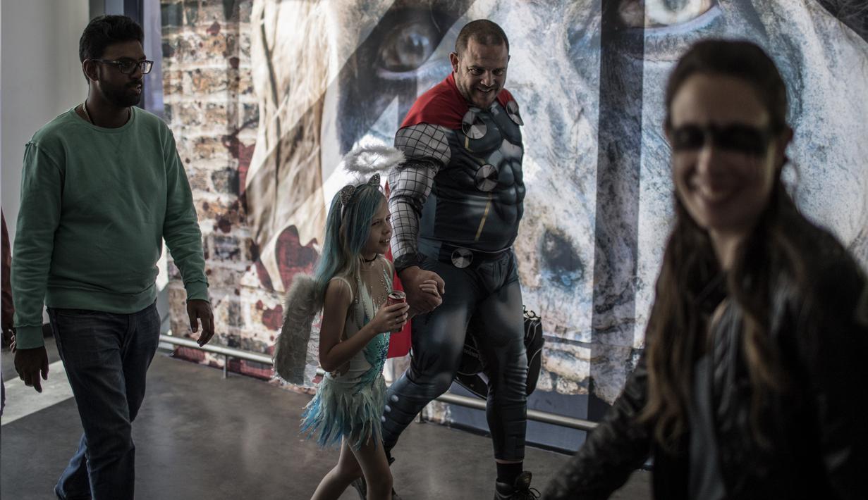 Seorang ayah mengajak anaknya menghairi International Comic Con di Kyalami Race Course, Johannesburg, Afrika Selatan (14/9). Comic Con digelar pada tahun 1970. (AFP Photo/Marco Longari)