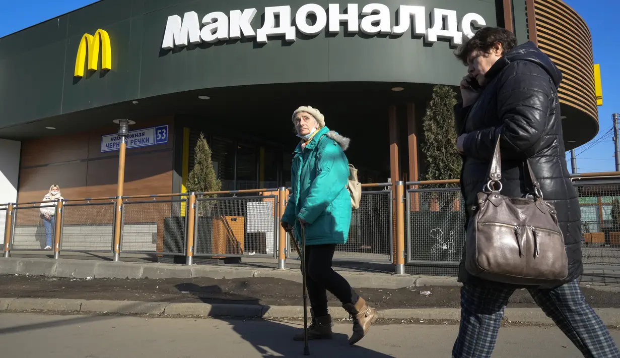 Perempuan berjalan melewati restoran McDonald's yang tertutup untuk pengunjung di St. Petersburg, Rusia, Selasa (15/3/2022). Gerai makanan siap saji McDonald's resmi menutup 850 gerainya yang beroperasi di Rusia pada 14 Maret 2022. (AP Photo)