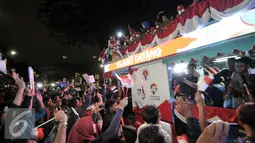 Warga menyambut arak-arakan atlet Indonesia yang berjuang di Olimpiade Rio 2016, Jakarta, Selasa (23/8). Setibanya di Tanah Air, atlet Olimpiade diarak menggunakan bus Bamdros menuju gedung Kementerian Pemuda dan Olahraga. (Liputan6.com/Yoppy Renato)