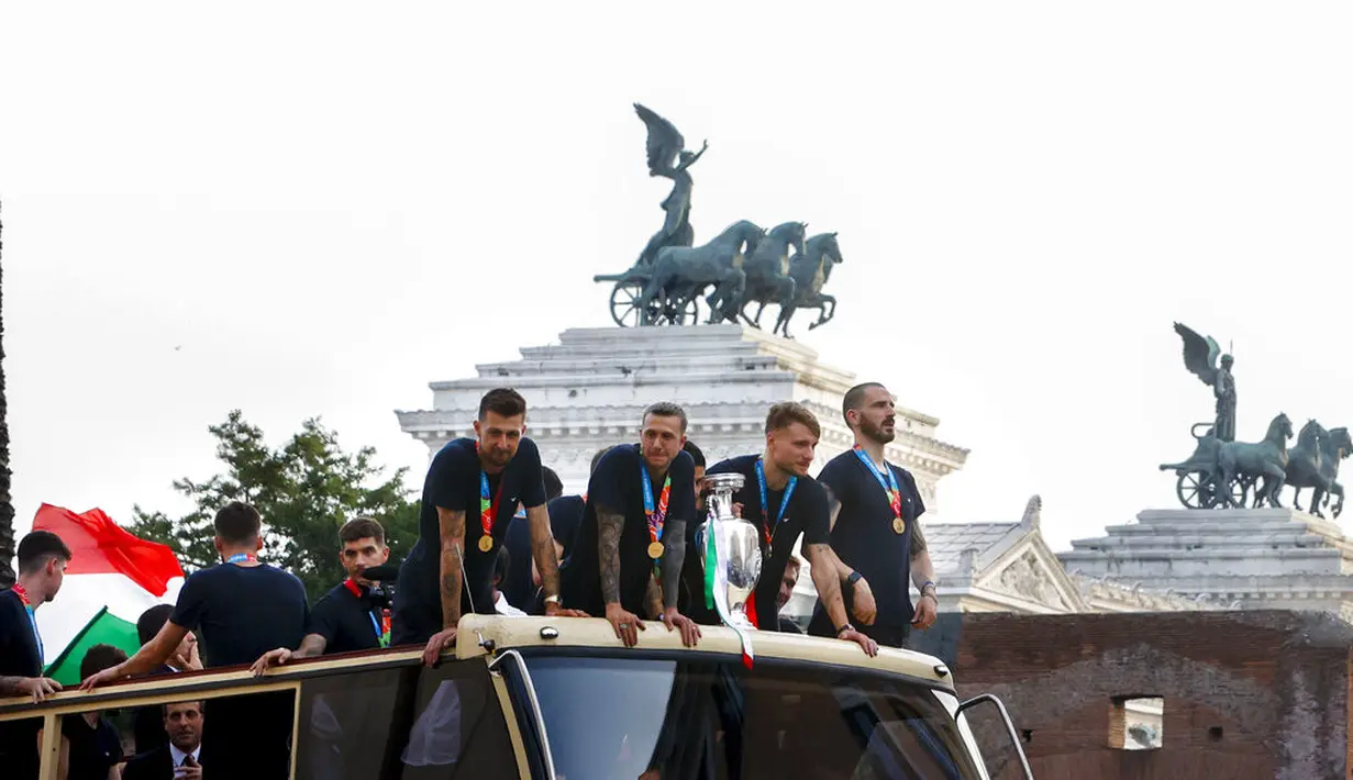 Para pemain Italia berada di atas bus saat perayaan juara Euro 2020 di Roma, Senin (12/7/2021). Italia mengalahkan Inggris 3-2 dalam adu penalti setelah bermain imbang 1-1 pada final Euro 2020 di stadion Wembley di London. (AP Photo/Riccardo De Luca)