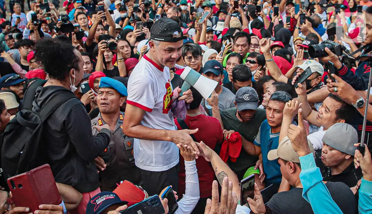 Bakal calon presiden dari PDIP yang juga Gubernur Jawa Tengah Ganjar Pranowo (tengah) menyapa pendukungnya saat berolahraga di Kompleks Stadion Utama Gelora Bung Karno (SUGBK), Jakarta, Minggu (30/4/2023). (Liputan6.com/Faizal Fanani)