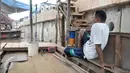 Mami menunggu warga yang hendak menyeberang menggunakan perahu eretan, Jakarta, Rabu (28/12). Meski penumpang tak seramai dulu, perahu eretan tetap bertahan diantara tembok beton normalisasi kali Ciliwung. (Liputan6.com/Yoppy Renato)