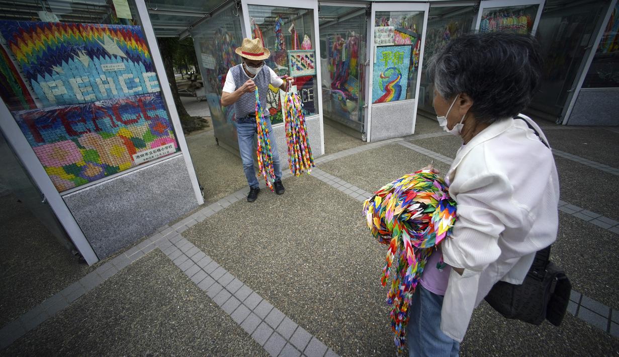 Hatsue Onda (kanan) dan Kengo Onda menawarkan ribuan origami kepada para korban bom atom 1945 di dekat Museum Peringatan Perdamaian Hiroshima, Hiroshima, Jepang, Senin (3/8/2020). Jepang akan memperingati 75 tahun bom atom di Hiroshima pada 6 Agustus 2020. (AP Photo/Eugene Hoshiko)