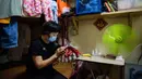 Wong Mei-ying (70) mengenakan masker sebagai tindakan pencegahan terhadap coronavirus novel COVID-19 bersantai sambil melihat ponselnya saat duduk di kasur pada 14 Mei 2020. flat yang telah dibagi menjadi enam bilik di Wilayah Baru Hong Kong.  (AFP/Anthony Wallace)