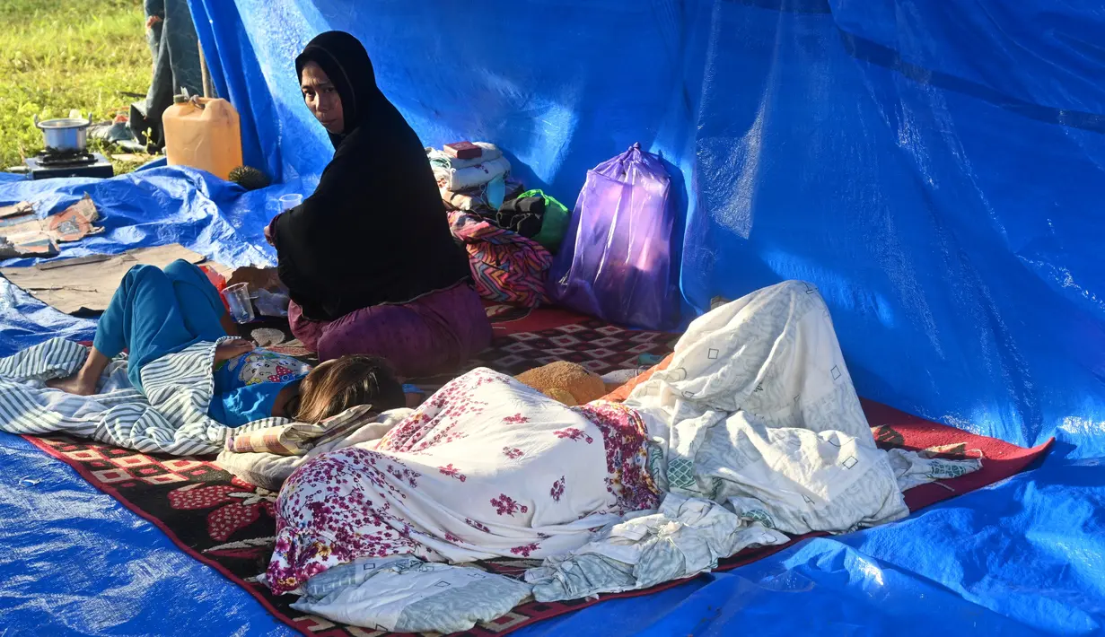 Sebuah keluarga beristirahat di tenda setelah gempa berkekuatan 6,2 di Mamuju, Senin (18/1/2021). Sebanyak 27.850 jiwa telah mengungsi di sejumlah posko pengungsian karena rumah mereka rusak akibat gempa. (AFP/Adek Berry)