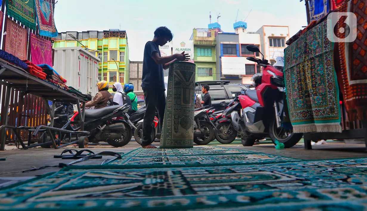 Pekerja menggulung karpet masjid pesanan pembeli di sebuah toko di kawasan Tanah Abang, Jakarta, Kamis (16/3/2023). (Liputan6.com/Angga Yuniar)