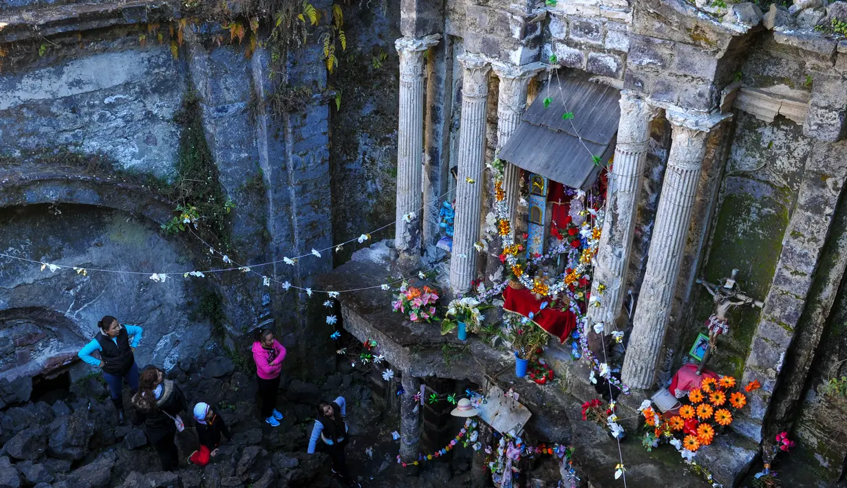 Wisatawan mengamati bangunan gereja San Juan Parangaricutiru di Angahuan, Meksiko, 17 Januari 2016. Gereja ini disebut sebagai keajaiban Tuhan karena luput dari sapuan lava gunung berapi pada  20 februari 1943 silam. (AFP PHOTO / Mario Vazquez)