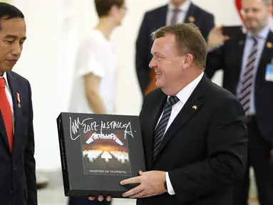 Perdana Menteri Denmark Lars Lokke Rasmussen memberikan Presiden Joko Widodo (Jokowi) cendera mata piringan hitam band Metallica usai pernyataan bersama dalam kunjungan kerja PM Denmark di Istana Bogor, Jawa Barat, Selasa (28/11). (AP/Dita Alangkara)