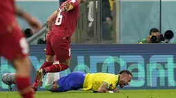 Penyerang Brasil, Neymar jatuh ke tanah di depan gelandang Serbia Sasa Lukic pada  matchday 1 Grup G Piala Dunia 2022 di Stadion Lusail Iconic, Jumat (25/11/2022) dini hari WIB. Bintang mereka, Neymar Jr mendapat cedera cukup serius dalam pertandingan itu. (AP Photo/Andre Penner)