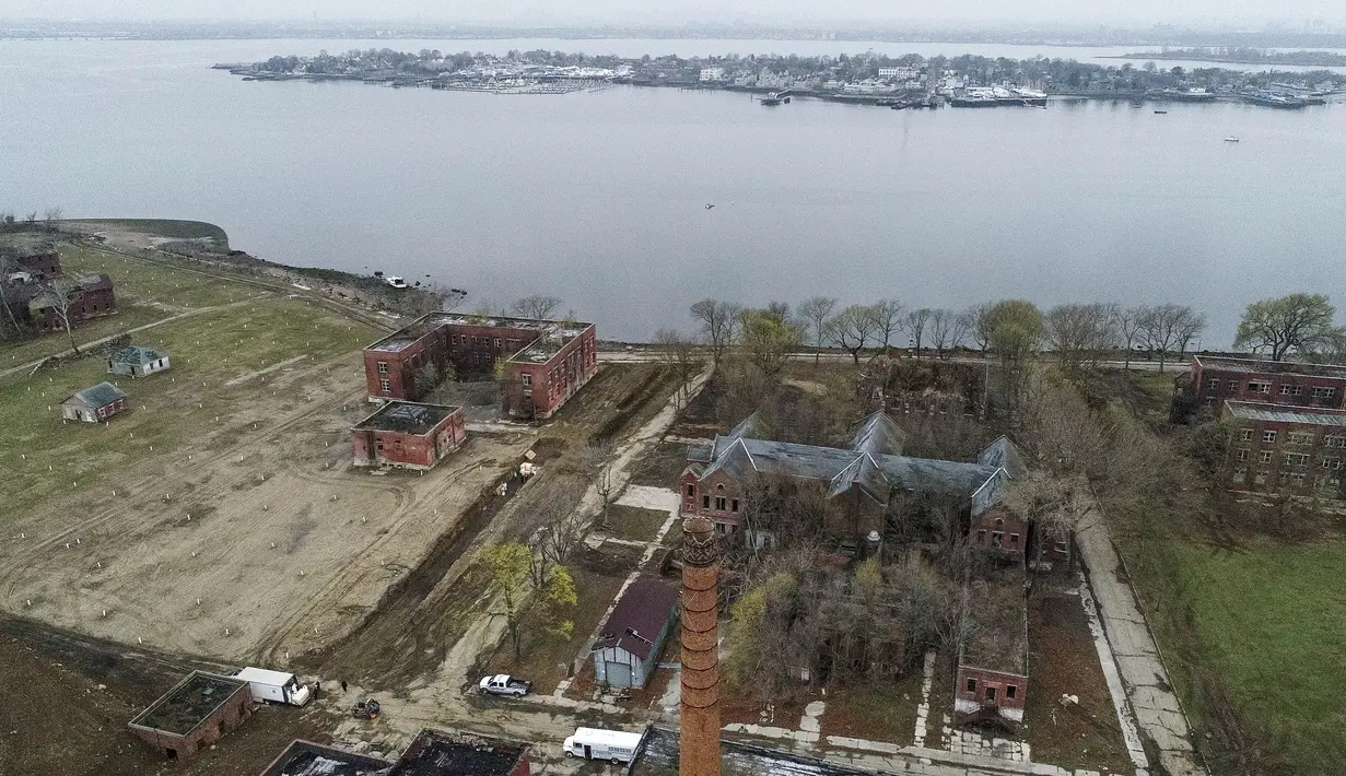 Suasana saat pekerja yang mengenakan alat pelindung diri mengubur jenazah dalam parit di Pulau Hart, Bronx, New York, Amerika Serikat, Kamis (9/4/2020). Sebelum menjadi tempat pemakaman korban virus corona COVID-19, Pulau Hart lebih dari 150 tahun menjadi kuburan massal. (AP Photo/John Minchillo)
