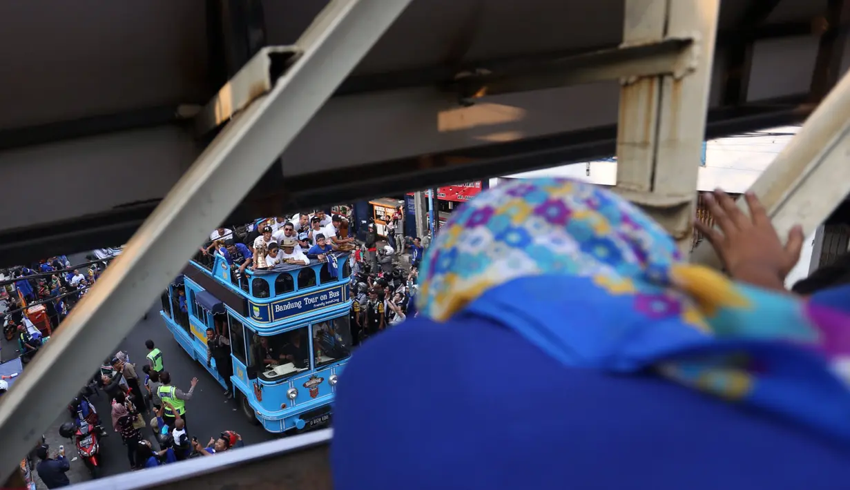 Seorang ibu menyambut pemain Persib Bandung dari jembatan penyeberangan saat berlangsungnya Pawai Persib Juara Piala Presiden, Minggu (25/10/2015). (Bola.com/Nicklas Hanoatubun)