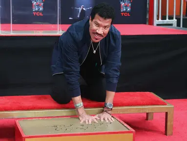 Penyanyi R&B AS, Lionel Richie mengabadikan cetak tangan dan kakinya di TCL Chinese Theatre, Hollywood, Rabu (7/3). Selama enam dekade aktif dalam dunia musik, Richie sukses menjual 100 juta album di seluruh dunia. (Tommaso Boddi/Getty Images/AFP)