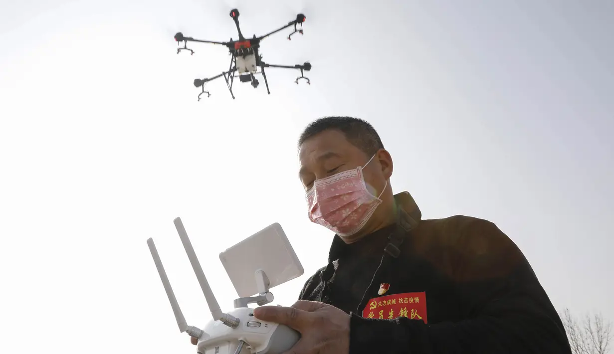 Seorang warga mengoperasikan drone yang membawa cairan desinfektan yang akan disemprotkan ke sebuah desa di Pingdingshan, Provinsi Henan, China (31/1/2020).  Menurut Komisi Kesehatan Nasional di China hingga 31 Januari, jumlah korban akibat wabah virus corona meningkat 213 orang. (AFP Photo/Str)