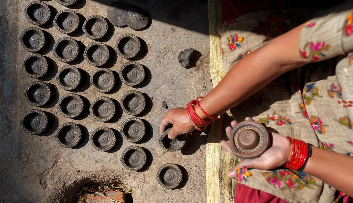 Seorang pembuat tembikar membuat lampu tanah untuk Festival Tihar atau Yama Panchak di Bhaktapur, Nepal, 21 Oktober 2022. Selama festival lima hari yang mirip dengan Festival Diwali di India tersebut, umat Hindu mendekorasi rumah dan tempat ibadah mereka. (AP Photo/Niranjan Shrestha)