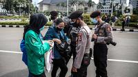 Polisi memeriksa barang bawaan mahasiswa yang akan berunjuk rasa di Patung Kuda, Jakarta, Selasa (20/10/2020). Pemeriksaan tersebut dilakukan untuk memastikan unjuk rasa berjalan aman dan damai. (Liputan6.com/Faizal Fanani)