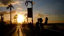 Orang-orang mengambil gambar terjangan ombak saat matahari terbenam di sepanjang garis pantai Beirut, Lebanon (26/10).  (AP Photo / Hassan Ammar)
