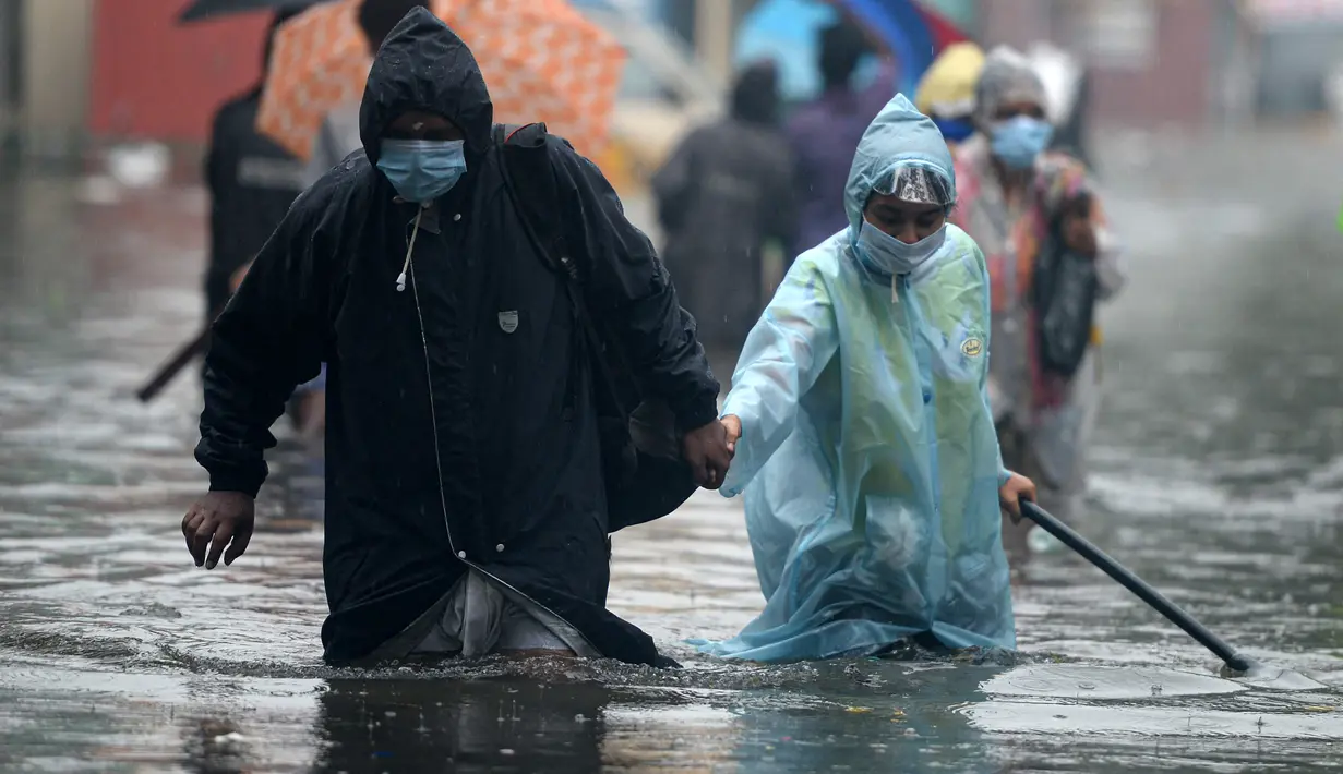 Orang-orang mengarungi jalan yang banjir setelah hujan lebat di Chennai, India (8/11/2021). Departemen Meteorologi India (IMD) memperkirakan lebih banyak curah hujan dalam beberapa hari mendatang. (AFP/Arun Sankar)