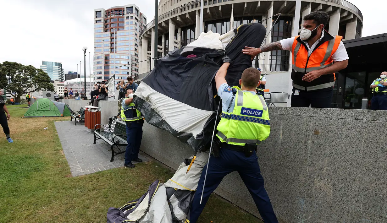 Polisi mengepak tenda di halaman parlemen pada hari ketiga demonstrasi menentang pembatasan Covid-19, yang terinspirasi oleh demonstrasi serupa di Kanada, di Wellington (10/2/2022). (AFP/Marty Melville)