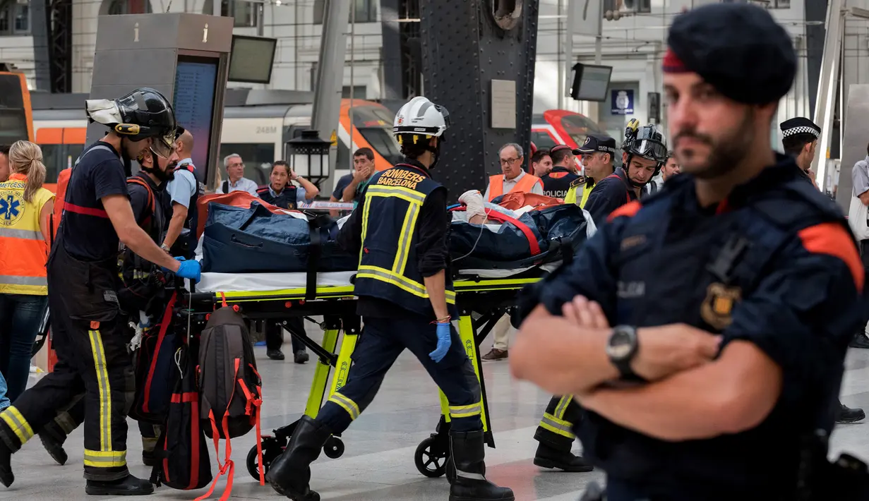 Seorang penumpang yang terluka dibawa pergi dengan tandu dari sebuah stasiun kereta api di Barcelona, Spanyol, Jumat (28/7). Pejabat pemerintah Catalan mengatakan bahwa 54 orang dirawat karena luka-luka akibat musibah tersebut. (AP Photo/Adrian Quiroga)