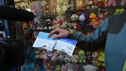 Seorang pria menunjukkan dua kemasan ganja kepada awak media yang baru dibeli di apotek di Montevideo, Uruguay (19/7). Apotek ini menjual ganja tersebut seharga USD 6,5 atau berkisar Rp 86.000 per lima gram. (AFP Photo/Miguel Rojo)