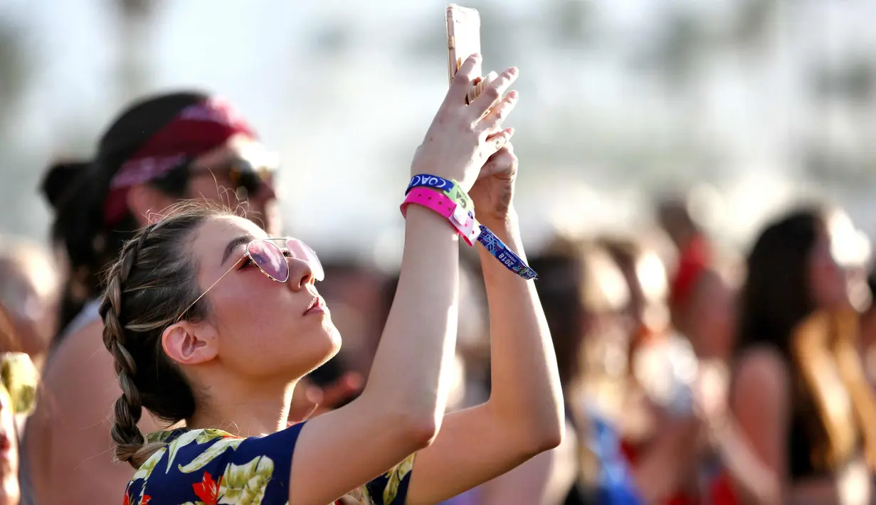 Seorang wanita mengambil gambar saat menghadiri Coachella Music & Arts Festival 2018 di Empire Polo Club di Indio, Calif (15/4). Festival ini selalu ditunggu oleh pencinta musik dunia dan selebriti Hollywood. (AFP Photo/Rich Fury)