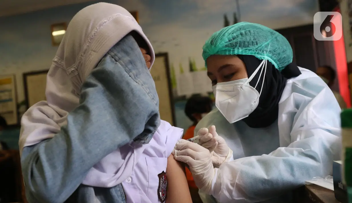 Seorang siswa menutup wajahnya saat disuntik vaksin COVID-19 Pfizer di SDN Panunggangan 5, Pinang, Kota Tangerang, Selasa (19/10/2021).  Pelaksanaan vaksinasi untuk pelajar usia 12 tahun ini dilakukan dalam rangka persiapan pelaksanaan pembelajaran tatap muka (PTM). (Liputan6.com/Angga Yuniar)