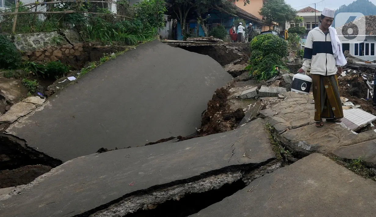 Warga melintas di jalan yang rusak  pascagempa bumi magnitudo 5,6 di Kampung Cisarua, Desa Sarampad, Kabupaten Cianjur, Jawa Barat, Rabu (23/11/2022). Berdasarkan data BNPB sebanyak 58.362 warga mengungsi akibat gempa bumi di Kabupaten Cianjur tersebut. (merdeka.com/Arie Basuki)