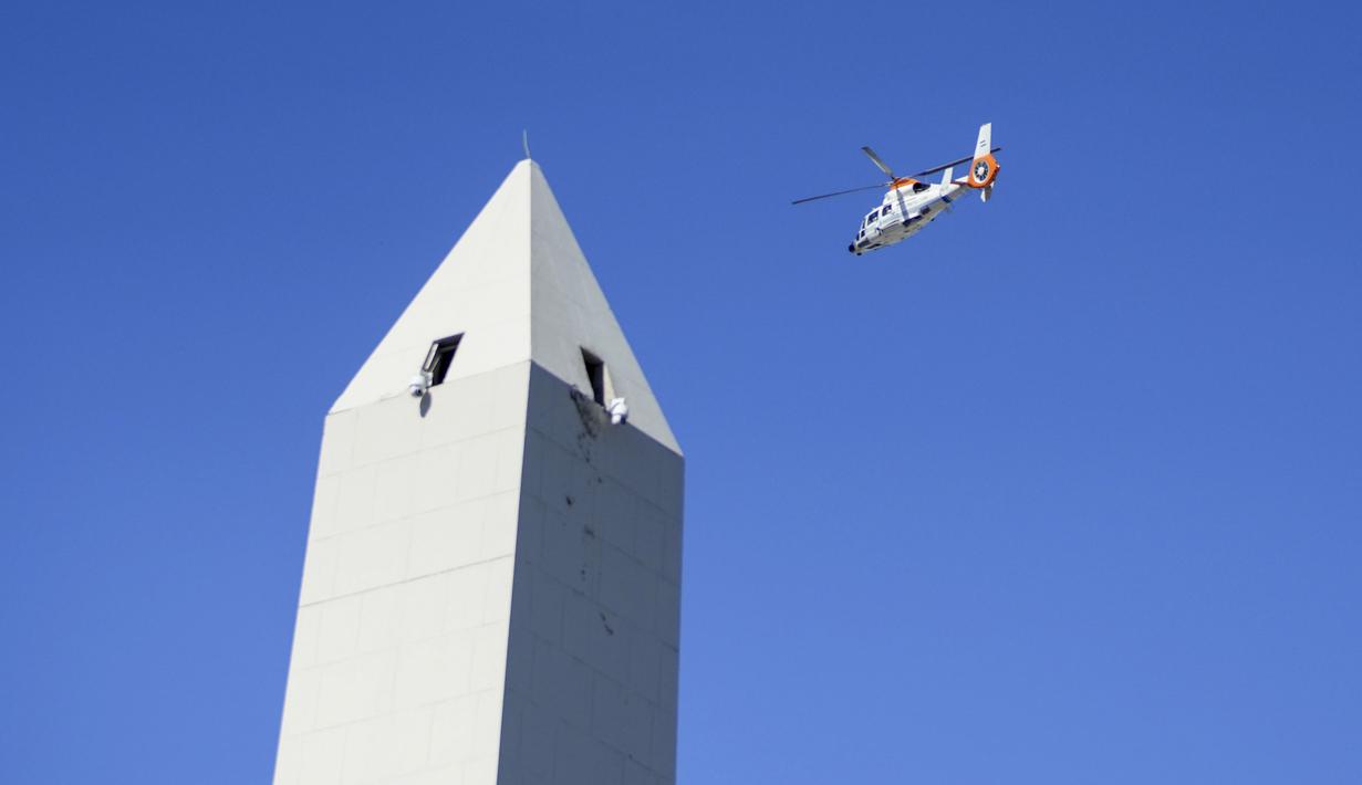 Helikopter yang membawa beberapa anggota timnas Argentina melintasi monumen Obelisk saat parade kemenangan Piala Dunia 2022 di provinsi Buenos Aires, pada 20 Desember 2022. Messi dan kolega terpaksa dievakuasi karena bus yang mereka gunakan tak bisa mencapai lokasi yang direncanakan akibat membeludaknya warga di jalanan. (AP Photo/Matilde Campodonico)