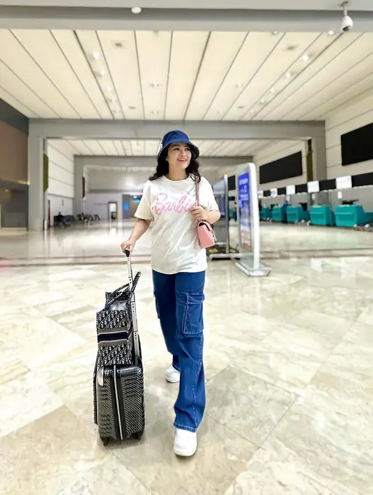 Tak jarang, Fitri Carlina yang merupakan istri dari seorang pilot ini juga mengunggah OOTD airport looknya. Ia tampil keren dengan atasan kaus putih bertuliskan Barbie, dipadu wide-leg denim pants dan topi yang serasi. [Foto: Instagram/fitricarlina]