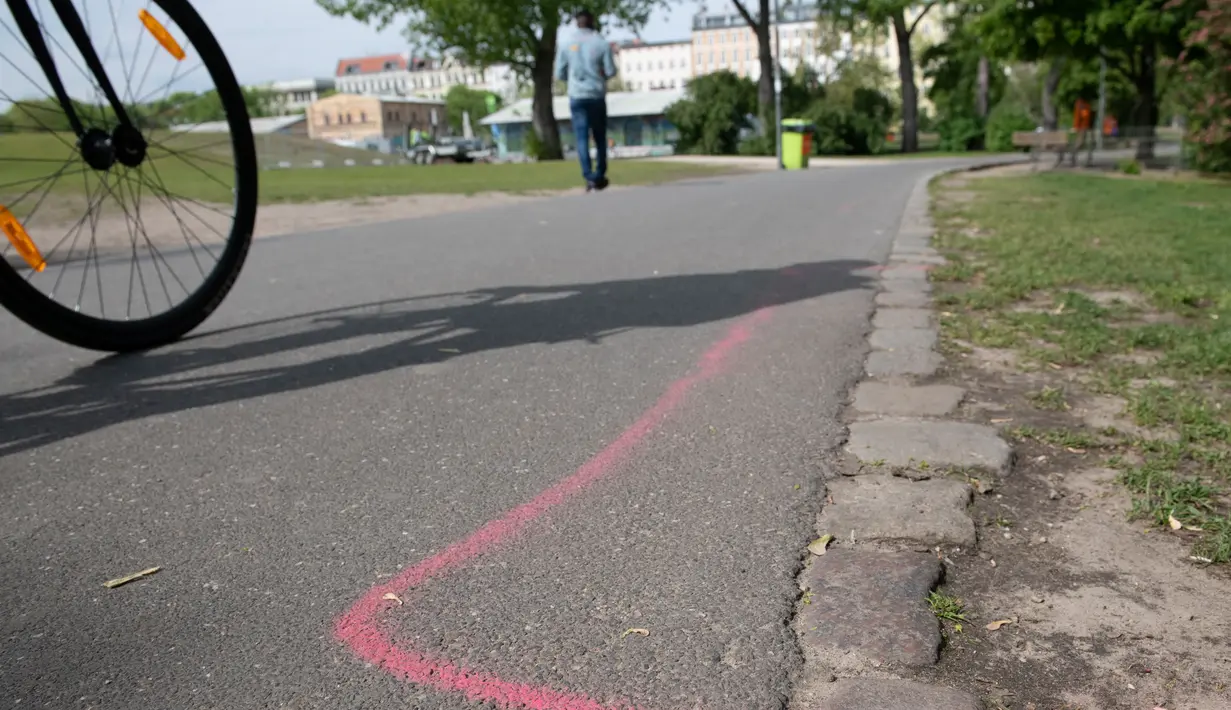 Gambar pada 8 Mei 2019 menunjukkan garis berwarna pink yang diperuntukkan bagi bandar narkotika di aspal Taman Goerlitzer, Berlin. Nantinya, para bandar hanya boleh bertransaksi di dalam zona berupa coretan kotak dengan cat semprot berwarna pink itu saja. (Paul Zinken / dpa / AFP)