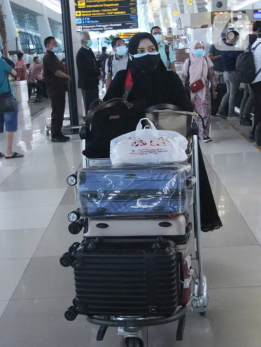Penumpang pesawat udara membawa barang bawaan di Terminal 3 Bandara Soekarno Hatta, Tangerang, Banten, Jumat (18/12/2020). PT Angkasa Pura II (Persero) atau AP II memprediksi lalu lintas sebanyak 2,1 juta penumpang pada periode angkutan Natal dan Tahun Baru 2021. (Liputan6.com/Angga Yuniar)