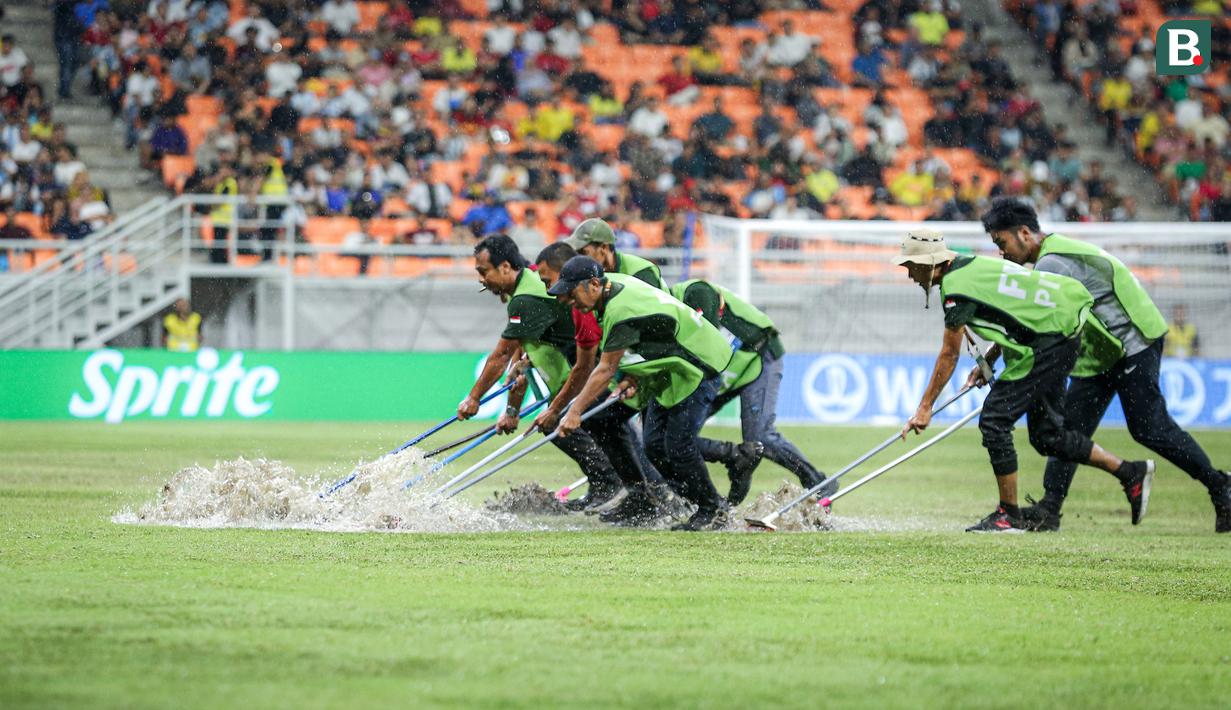 Sejumlah petugas menyingkirkan air yang menggenangi lapangan Jakarta International Stadium (JIS) jelang laga perempat final Piala Dunia U-17 2023 antara Timnas Brasil U-17 melawan Timnas Argentina U-17, Jumat (24/11/2023). (Bola.com/Bagaskara Lazuardi)